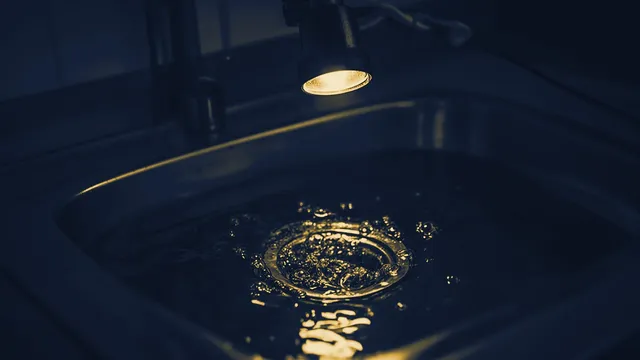Luchtbellen borrelen op door het water in een gootsteenafvoer, close-up